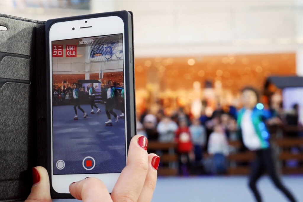 Visiteur filmant une animation roller disco avec son smartphone